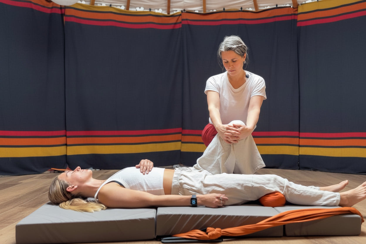 Person receiving a massage in a yurt-like setting with a person standing above them.